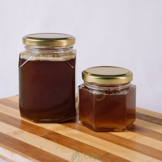 Two glass jars of pure bee honey with golden lids on a wooden board, Ceylon Mood