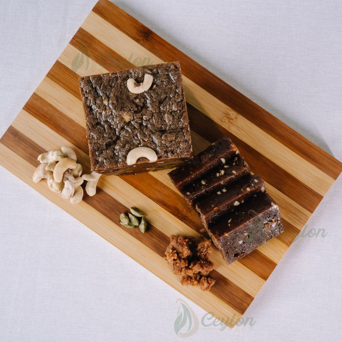 Top view of Kalu Dodol with cashew nuts and cardamom on a wooden board