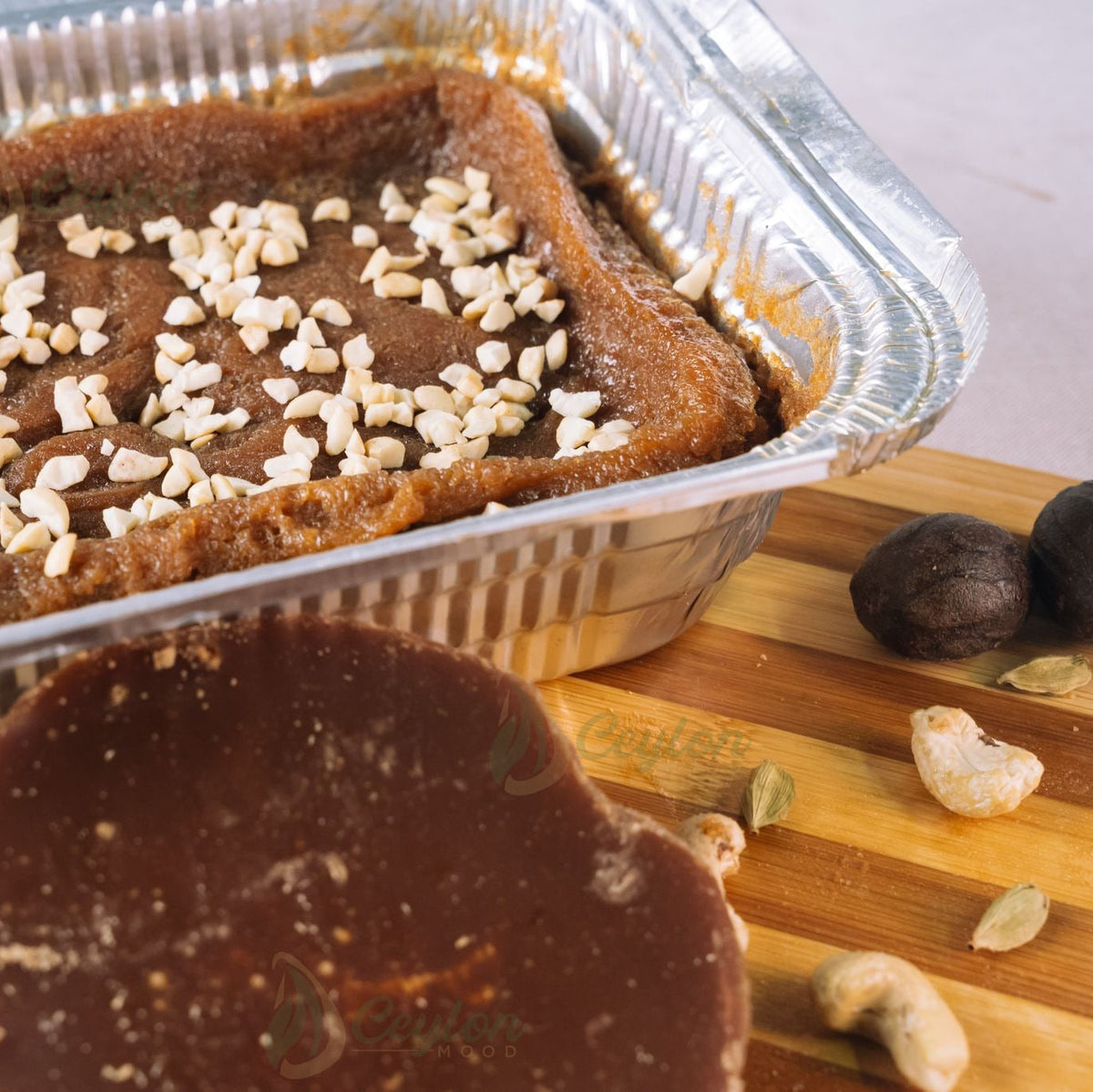 Watalappan in an aluminium foil basket topped with nuts, with kithul jaggery