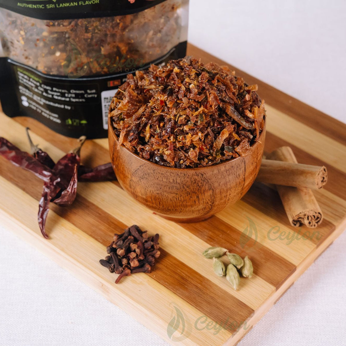 Sprats sambol in a wooden bowl with spices on a wooden board